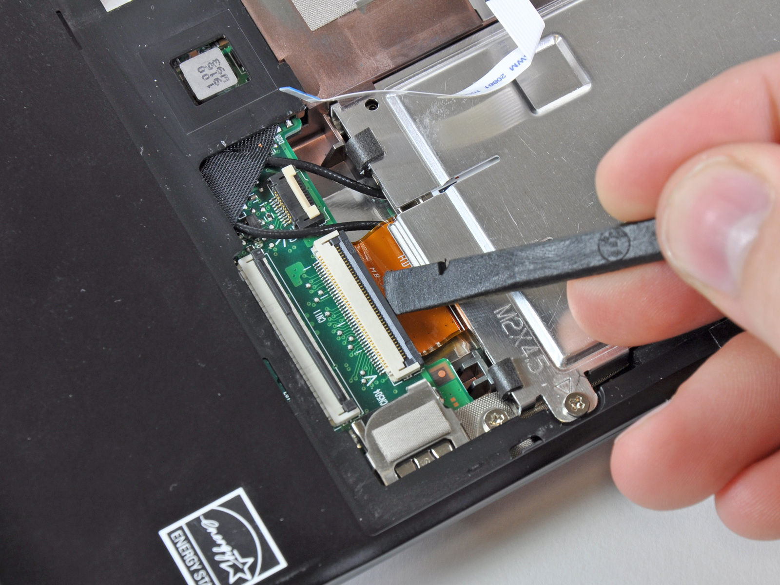 Étape 7 Disque Dur Utilisez votre ongle ou le bout plat d'un spudger pour retourner le rabat de retenue sur la prise câble ruban ZIF de la carte SIM.