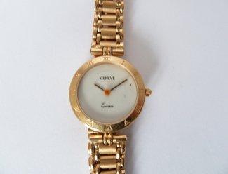 64 GENEVE Estimation : 700 / 900 Euros Adjugé(e) : 980 Euros GENEVE : bracelet-montre rond de dame en or, cadran blanc muet, la lunette à chiffres romains, le tour de bras à petits