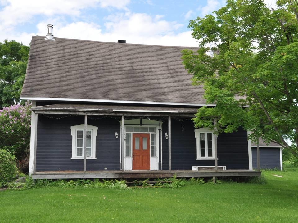 Maison québécoise avec une imposante porte centrale à imposte et vitres latérales;