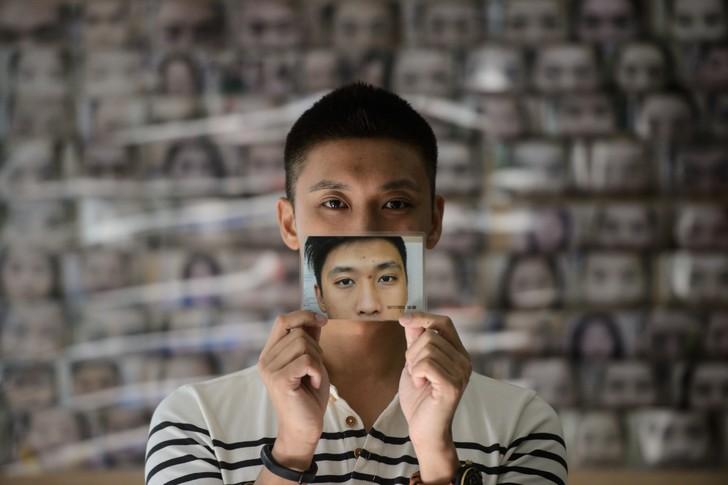 Un jeune homme montre une photo de lui-même et du changement de son visage après une épilation de ses sourcils, le 22 juillet 2016 à Hong Kong / AFP "Il y a des tournants dans la vie de quelqu'un et