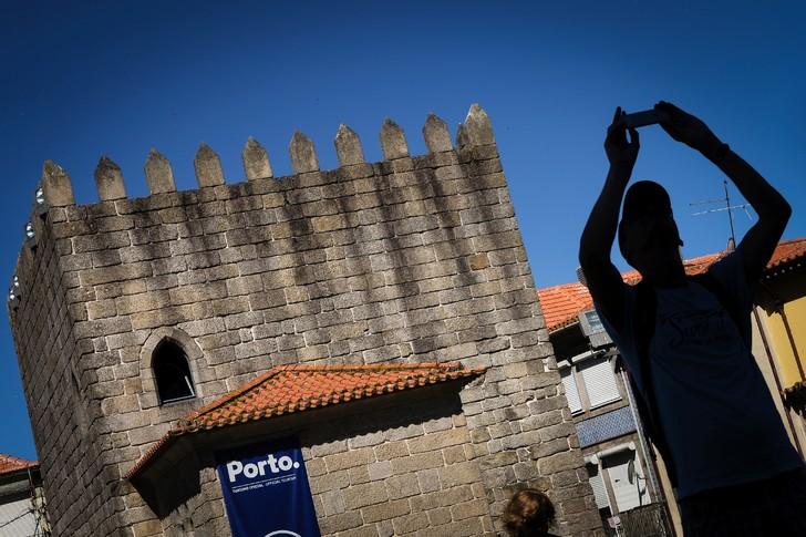Un touriste prend une photo près des tours Pitoes à Porto, le 25 juillet 2016 / AFP L'échafaudage qui cache depuis avril la vue sur l'imposant double escalier en bois sculpté aux marches écarlates